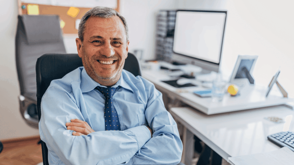 Smiling pathologist at a desk reviewing digital slides on dual monitors in a modern lab setting